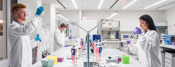 Plusieurs scientifiques de Novartis dans un environnement de laboratoire moderne et lumineux.