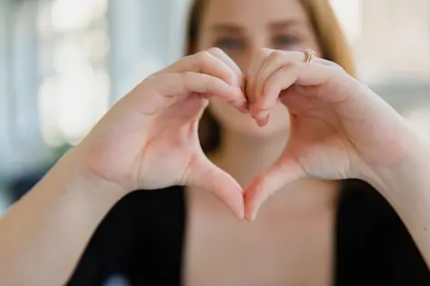 Mujer haciendo símbolo de corazón con sus manos